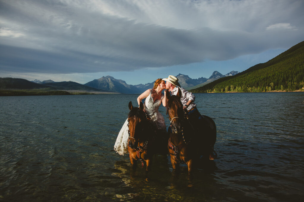 bride and groom horseback riding in the water in colorado