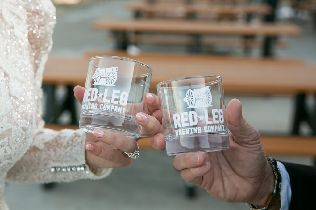 close up of elopement couple holding beer glasses