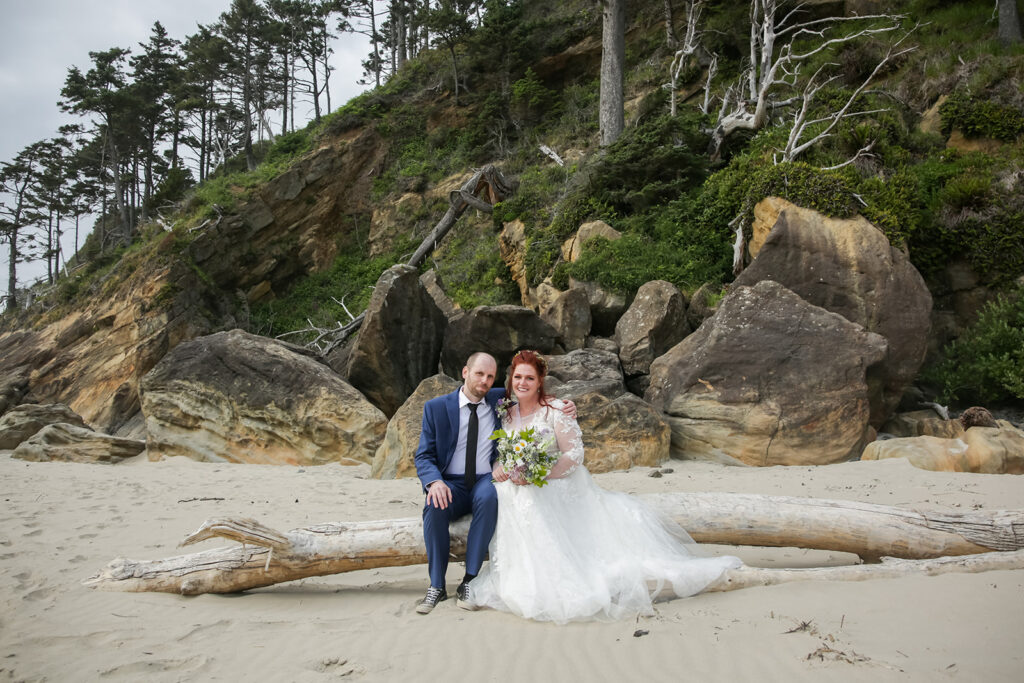 bride and groom sitting on a piece of drift wood during their hug point elopement