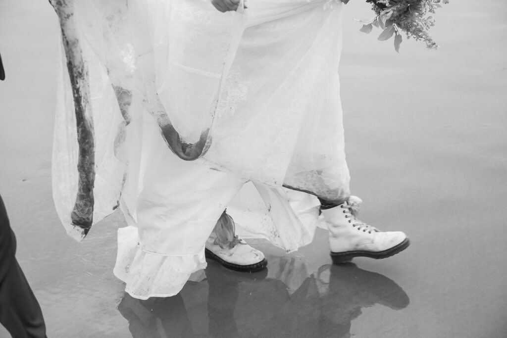 excited bride and groom running along the oregon coast